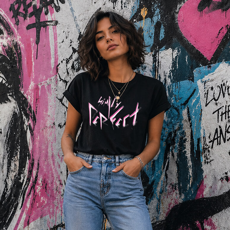 Woman wearing a black t-shirt with punk slogan style that says 'Simply Perfect' in front of a graffiti-covered wall.