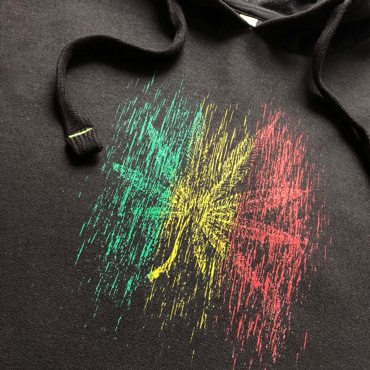 Black hoodie with a rasta color rainy effect hemp leaf graphic